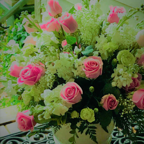 Pink roses and white flowers arranged in a white vase