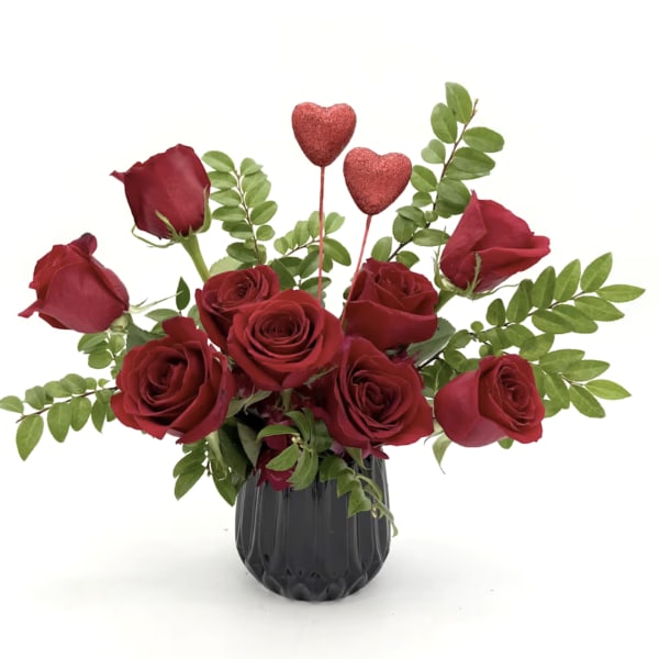 Red roses in a black vase with two glitter heart picks