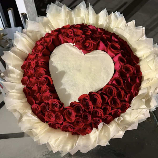 Heart-shaped arrangement of red roses with white wrapping around it