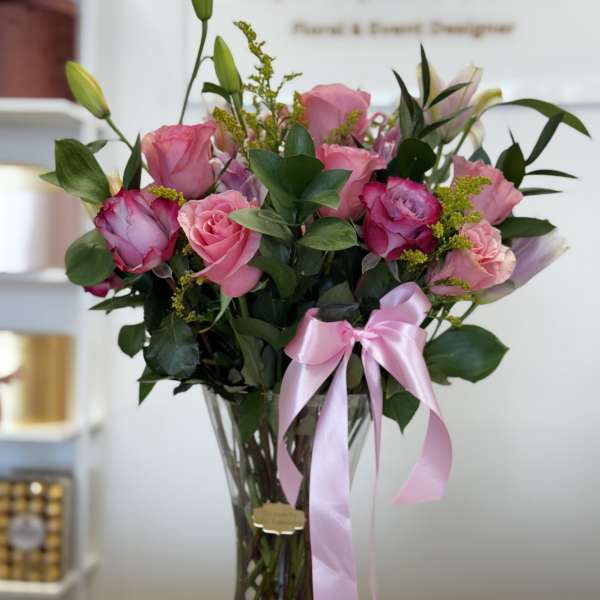 Pink roses in a clear glass vase with a pink ribbon