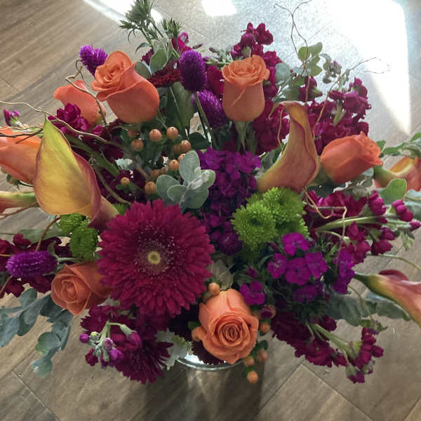 Bright mixed bouquet with orange roses and purple flowers in a vase