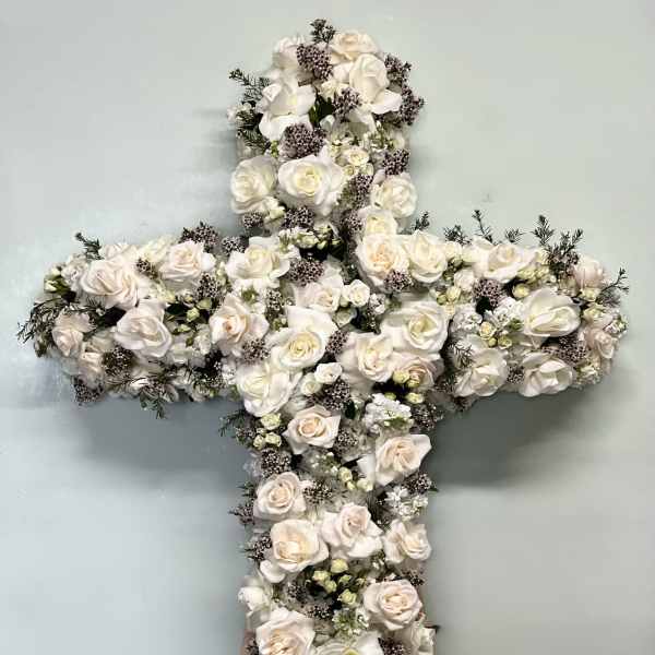 White floral cross arrangement with roses on a stand