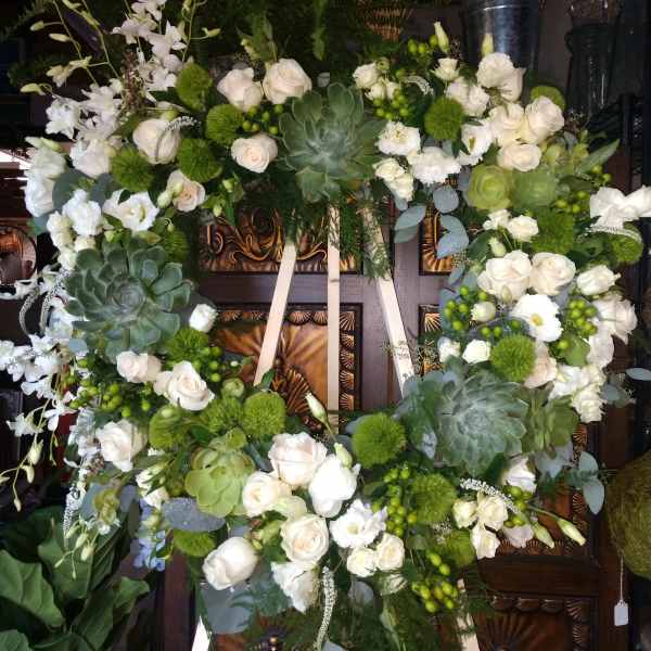 Large white floral wreath with roses and succulents on an easel