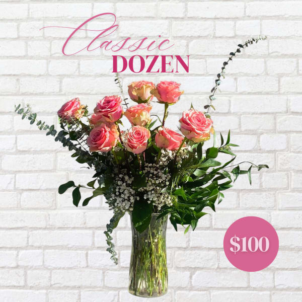 Pink roses arranged in a clear glass vase with greenery