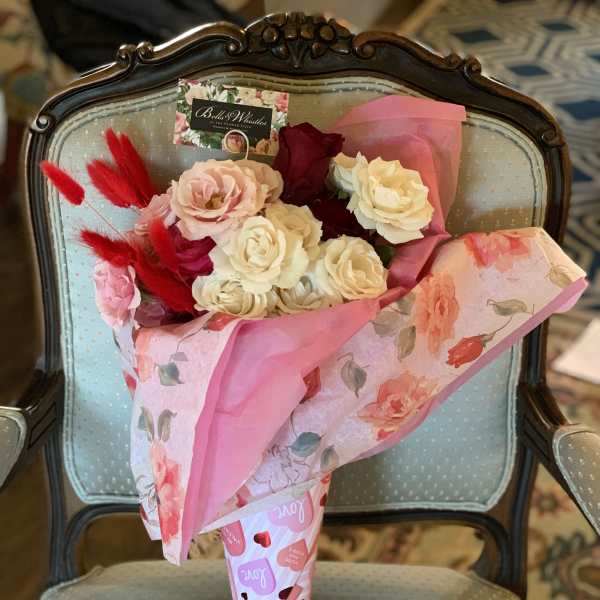 Bouquet of pink, white, and red roses wrapped in pink paper
