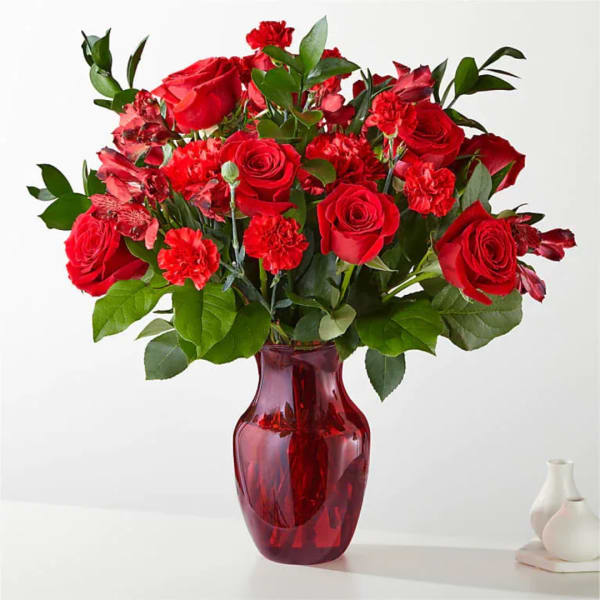 Red roses and carnations in a red glass vase