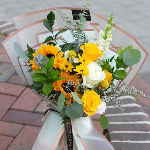 Bouquet of yellow and white flowers wrapped in translucent paper