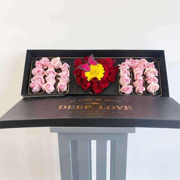 Heart-shaped rose box with pink and red roses and a yellow flower