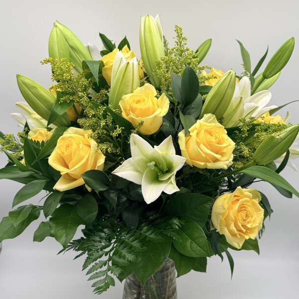 Yellow roses and white lilies in a glass vase