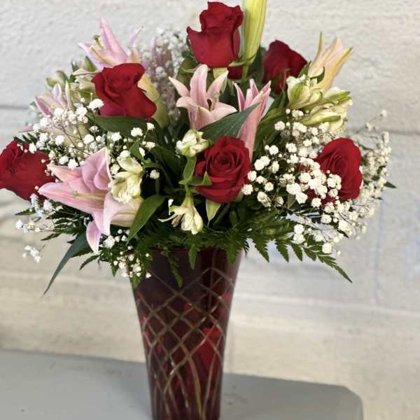 Red roses and pink lilies arranged in a tall vase