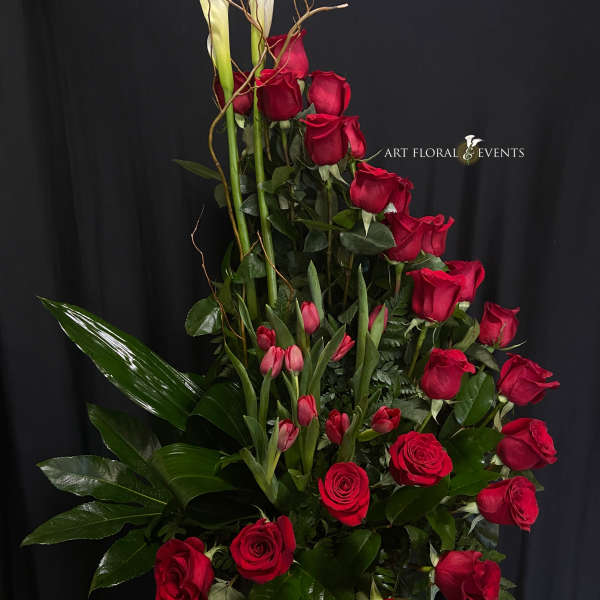 Tall arrangement of red roses and pink tulips with white calla lilies
