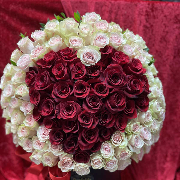 Heart-shaped bouquet of red and pale pink roses in a black box with a red ribbon