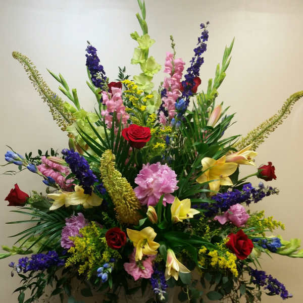 Large mixed floral arrangement in a pedestal vase with roses and lilies