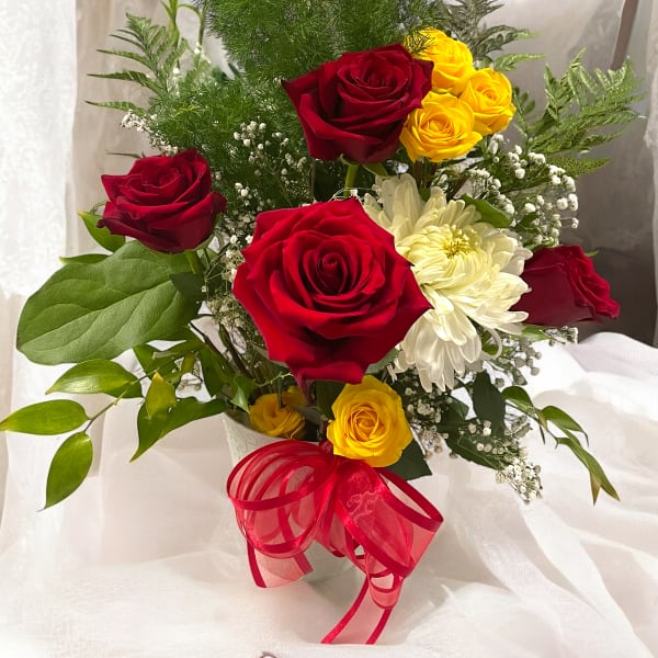 Bouquet of red and yellow roses with white flowers in a white vase