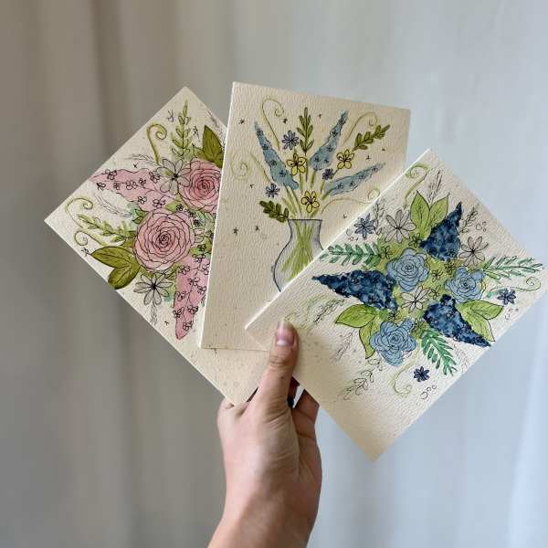 Hand holding three floral greeting cards with watercolor flowers