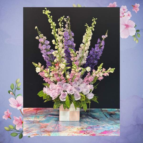 Tall arrangement of lavender and white flowers in a square vase