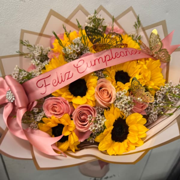 Bouquet of sunflowers and pink roses with a pink birthday ribbon