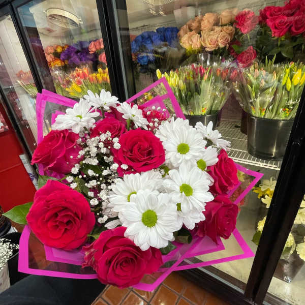 Hand-tied bouquet of hot pink roses, white daisies, and baby's breath in bright pink wrap