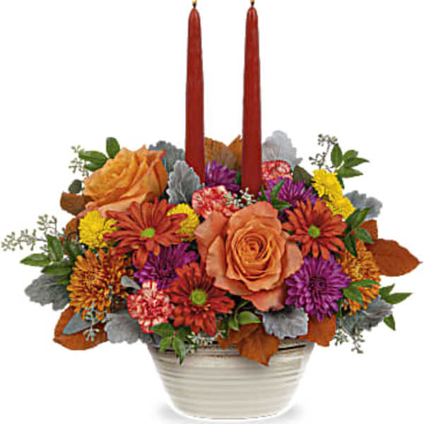 Autumn floral centerpiece with two red taper candles in a white bowl vase