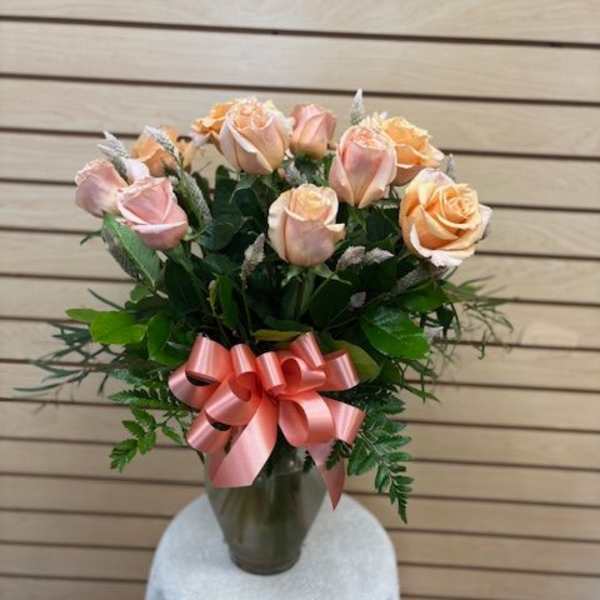 Pink and peach roses in a glass vase with a pink ribbon bow