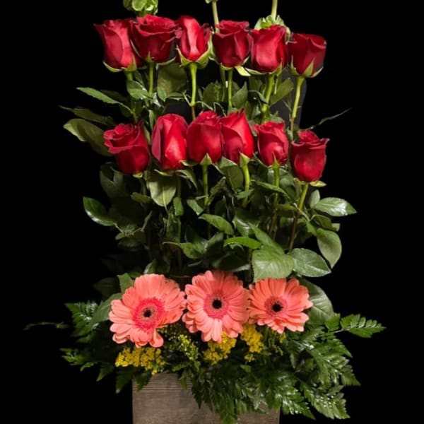 Tall arrangement of red roses and pink gerbera daisies in a square vase