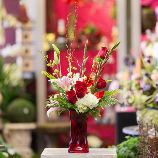 Red roses and white lilies in a red glass vase