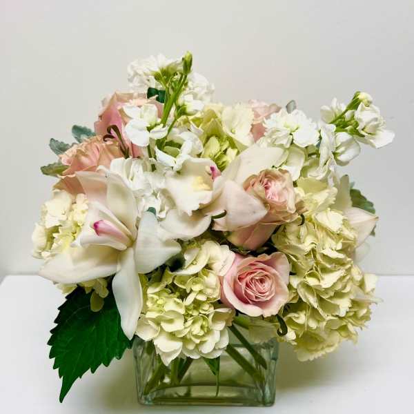 Pink roses and white lilies arranged in a square glass vase