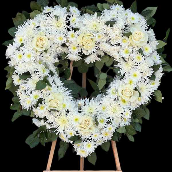 Heart-shaped white floral wreath on a wooden easel