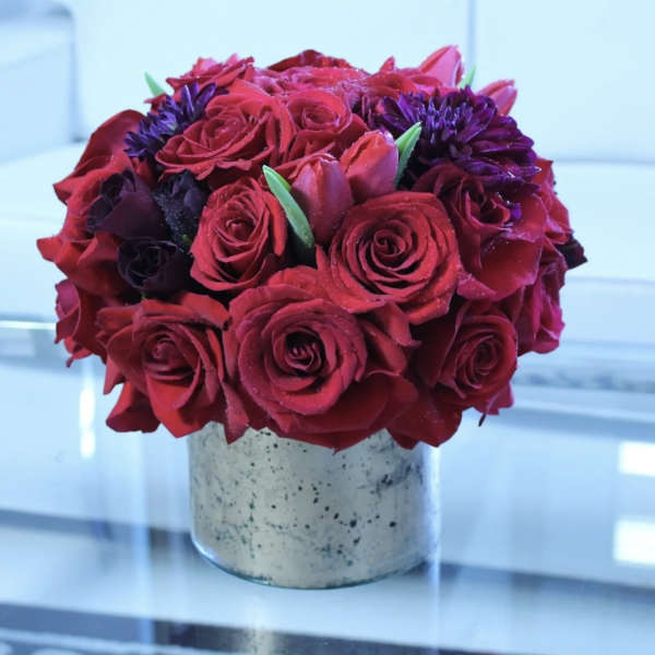 Red rose bouquet with purple flowers in a speckled vase