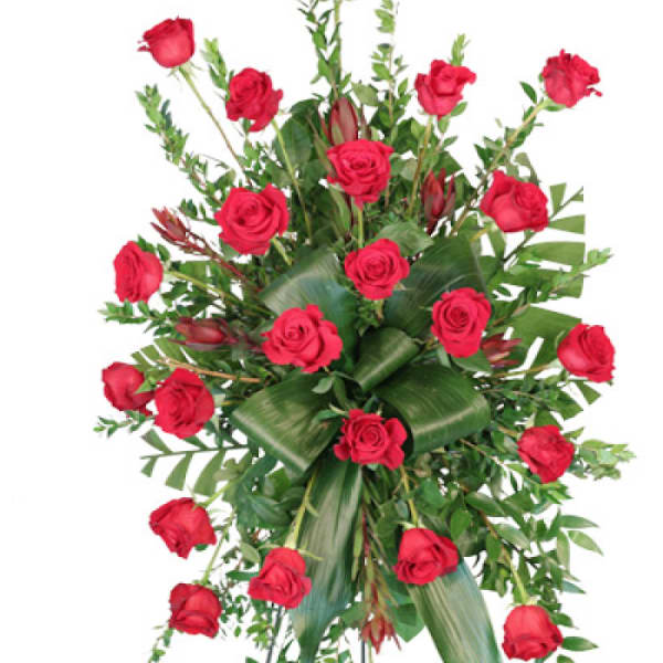 Standing spray of red roses with greenery on an easel