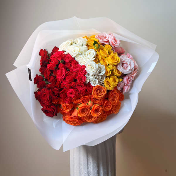 Large bouquet of multicolored roses wrapped in white paper