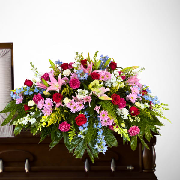 Large floral casket spray with roses, lilies, and mixed blooms