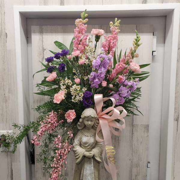 Tall floral arrangement with pink and purple blooms on a statue base
