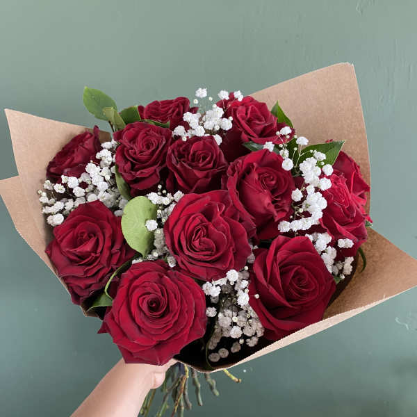 Bouquet of red roses with white baby's breath in brown paper