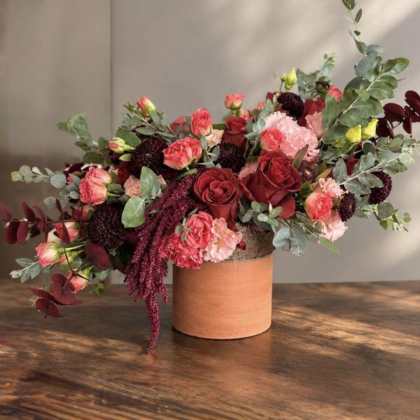 Mixed bouquet of red and pink flowers in a terracotta vase