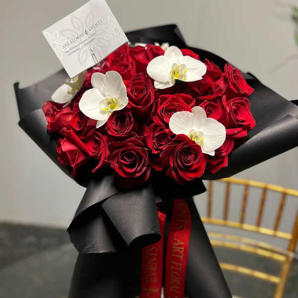 Bouquet of red roses with white orchids wrapped in black paper