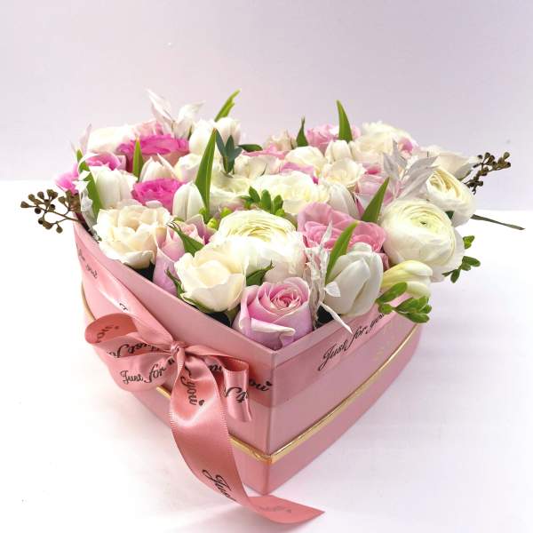 Pink heart-shaped box of white and pink roses with a ribbon bow