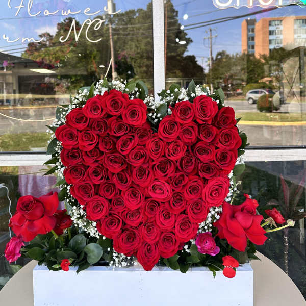 Heart-shaped red rose arrangement in a white box