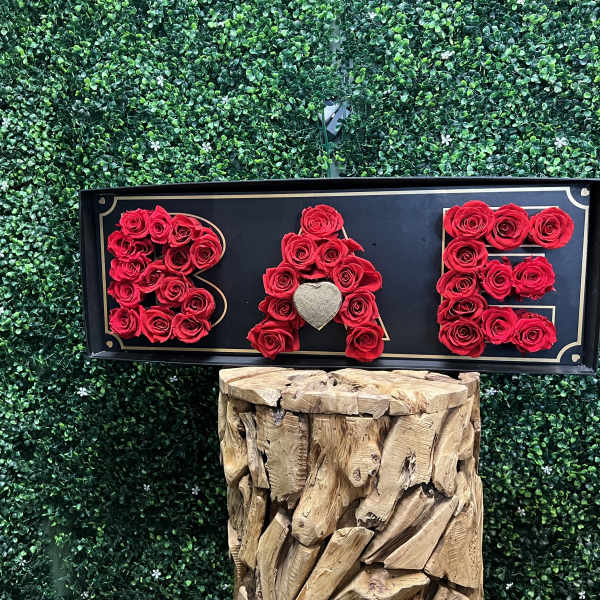 Red roses arranged to spell BAE on a black sign
