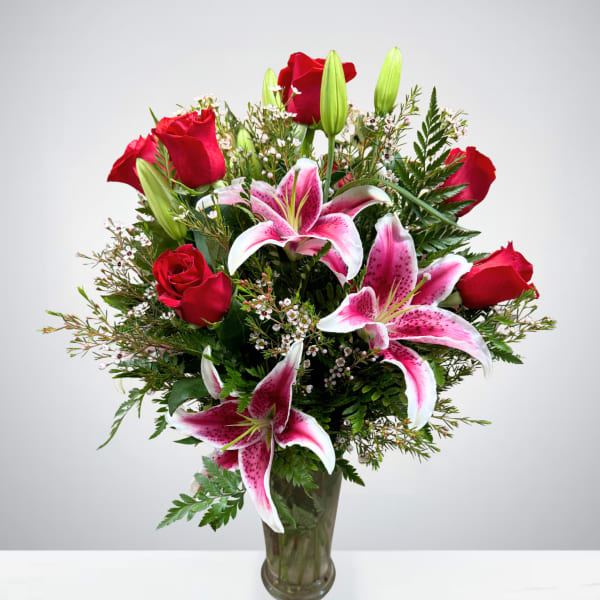 Bouquet of red roses and pink lilies in a glass vase