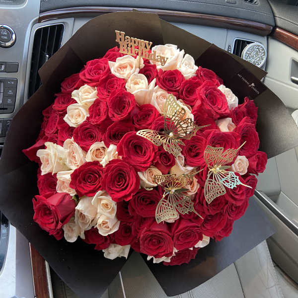 Bouquet of red and blush roses with butterfly picks and a Happy Birthday topper