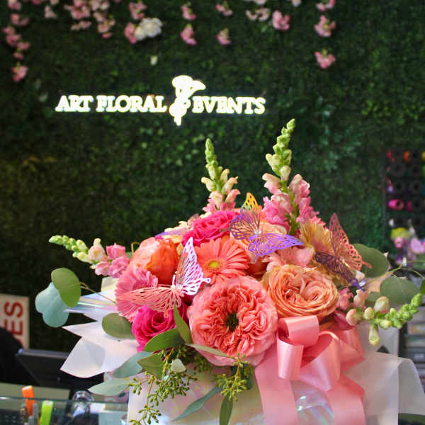Pink and peach flower bouquet in a white box with a ribbon