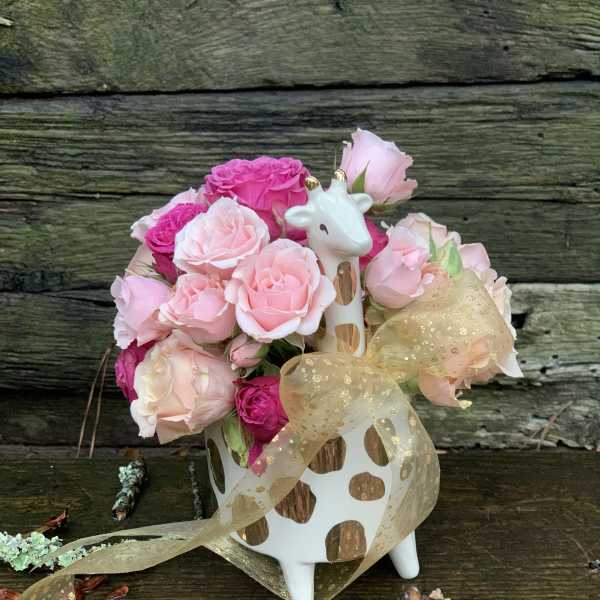 Pink rose bouquet in a giraffe-shaped vase with a gold ribbon