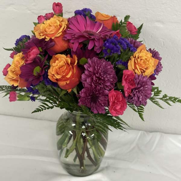 Mixed bouquet of purple, pink, and orange flowers in a glass vase