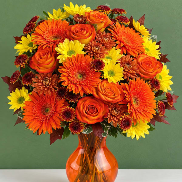 Orange and yellow mixed bouquet in an orange glass vase
