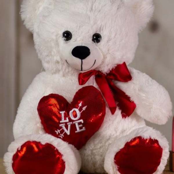 White teddy bear holding a red heart with a ribbon