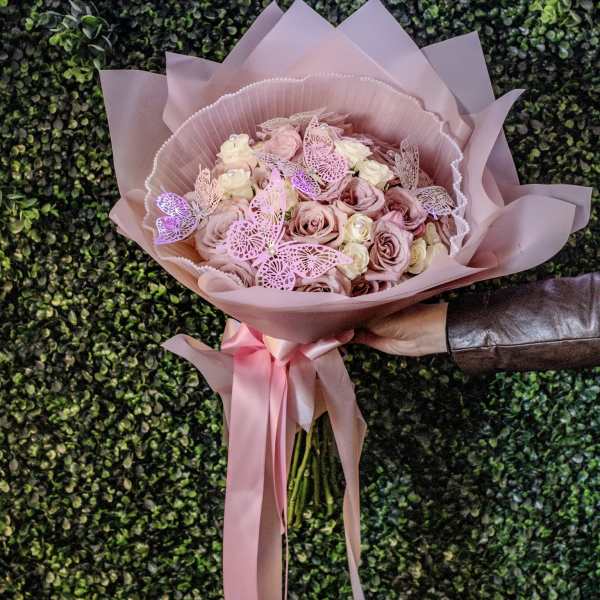 Pink rose bouquet wrapped in blush paper with a satin ribbon