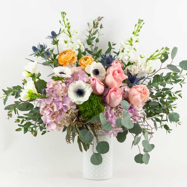 Mixed bouquet of pastel flowers in a white vase