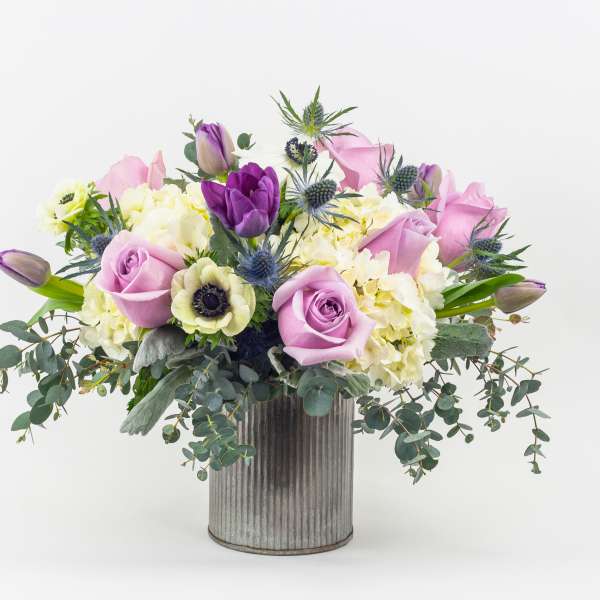 Lavender roses and purple tulips in a ribbed metal vase
