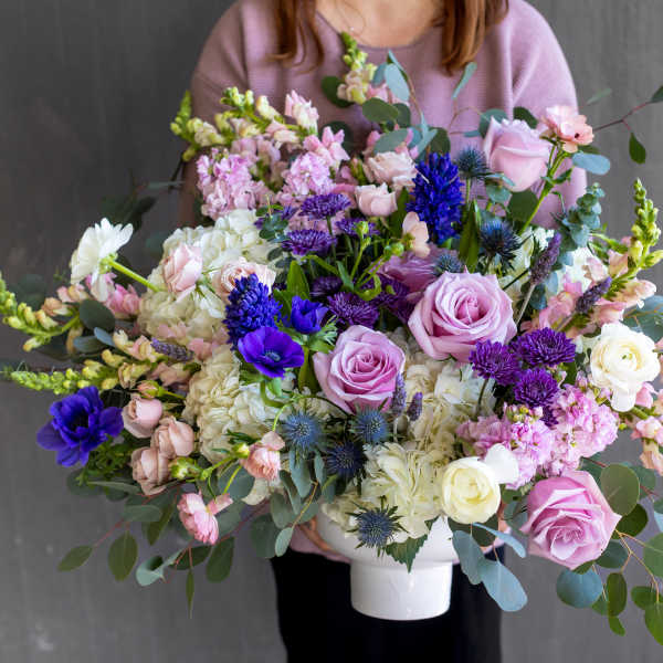 Large mixed bouquet in a white vase with pink, white, and purple flowers